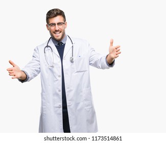 Young Handsome Doctor Man Over Isolated Background Looking At The Camera Smiling With Open Arms For Hug. Cheerful Expression Embracing Happiness.