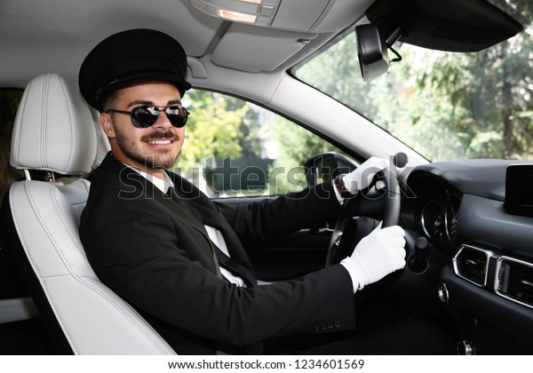 Young\
handsome driver in luxury car. Chauffeur\
service