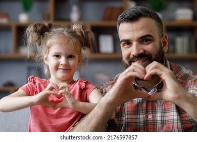 Young Handsome Father And Little Cute Daughter Smiling Looking At Camera Showing Symbol Making With Fingers Heart Shape Sign Of Love. Family Love And Family Bond Concept. Father's Day.