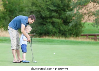 young handsome father teaching his little son how to play golf