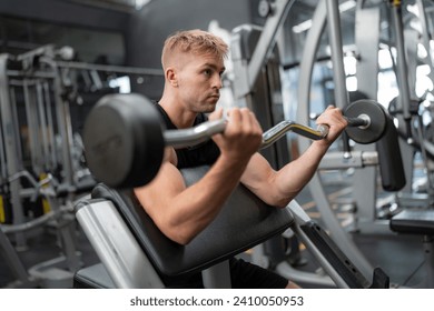 Young handsome fit man in gym working out, lifting bar of barbell, flexing muscles. - Powered by Shutterstock