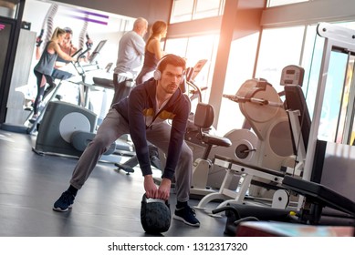 Young Handsome Fitness Man Lifting Dumbells During An Exercise Class In A Gym 