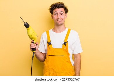 young handsome guy looking puzzled and confused. handyman with a drill concept