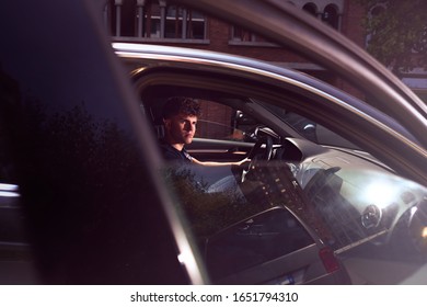 A Young Handsome Guy Sits In The Car With The Door Open And Looks Seductively Into The Camera