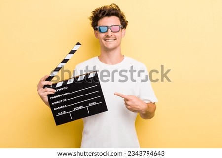 young handsome guy smiling cheerfully, feeling happy and pointing to the side. movie concept