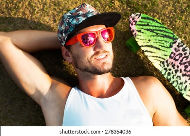 Young handsome hipster man relaxed and  lay at sunny day on the park on tropical island in cool summer sunglasses,reflecting palm trees in sunglasses.Stylish young beard man,hipster outfit. - Powered by Shutterstock