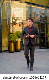 Young Handsome Hispanic Businessman Walking Outside The Office Building