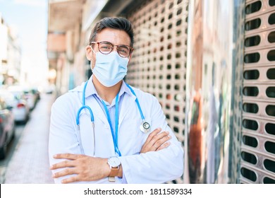 Young Handsome Hispanic Doctor Wearing Uniform And Coronavirus Protection Medical Mask Standing At Town Street.