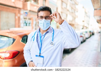 Young Handsome Hispanic Doctor Wearing Uniform And Coronavirus Protection Medical Mask Standing At Town Street.