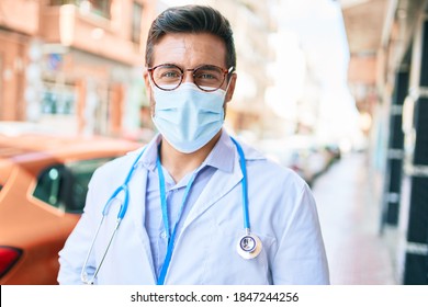 Young Handsome Hispanic Doctor Wearing Uniform And Coronavirus Protection Medical Mask Standing At Town Street.