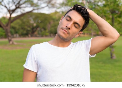 Young Handsome Hispanic Man Stretching Neck At The Park