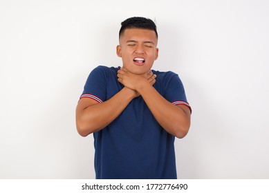 Young handsome hispanic man wearing casual t-shirt standing over white isolated background shouting suffocate because painful strangle. Health problem. Asphyxiate and suicide concept.