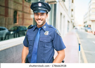 Young Handsome Hispanic Policeman Wearing Police Uniform Smiling Happy Standing With Smile On Face At Town Street.