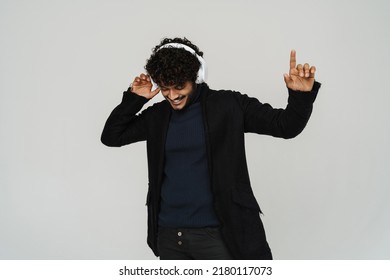 Young Handsome Indian Man Dancing In Headphones Over Isolated Grey Background