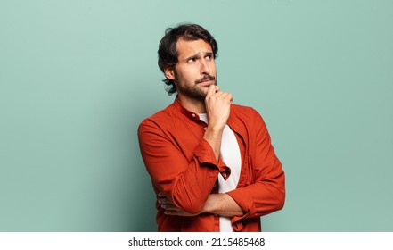 Young Handsome Indian Man Feeling Thoughtful, Wondering Or Imagining Ideas, Daydreaming And Looking Up To Copy Space