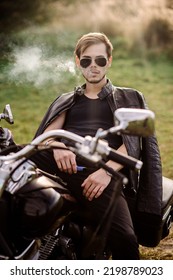 Young Handsome Male Biker Is Sitting And Smoking On Motor Bike