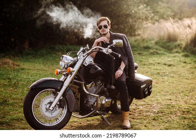 Young Handsome Male Biker Is Sitting And Smoking On Motor Bike