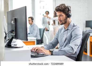 Young handsome male customer support phone operator with headset working in call center. - Shutterstock ID 722489089