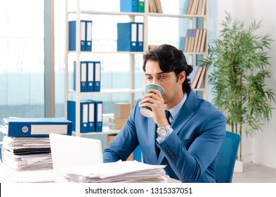 Young handsome male employee with too much work in the office   - Shutterstock ID 1315337051