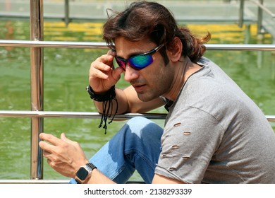 Young Handsome Male With Ponytail Hairstyle, Street King Style Of Man Gesture On Swimming Pool  