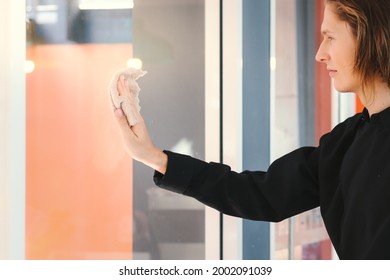 Young Handsome Male Staff Waiter Holding Cleaning Clothe For Wiping Window Glass At Café Coffee Shop, Cleaning Up The Restaurant.