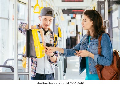 Young handsome male student helping attractive helpless female buying the ticket with ticket machine in modern tram during ride. Communication, acquaintance, friendship concept. - Shutterstock ID 1475465549
