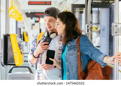 Young handsome male student helping attractive helpless female buying the ticket with ticket machine in modern tram during ride. Communication, acquaintance, friendship concept. - Shutterstock ID 1475465552