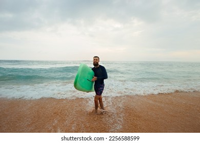 Young handsome male surfer with a surfboard on a sandy beach at ocean . Summer, vacation, sea - Shutterstock ID 2256588599