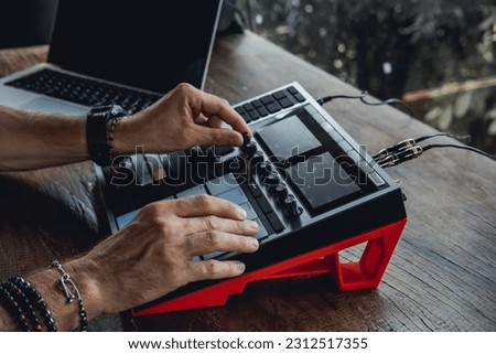 young handsome man with a beard and dark hair sits at a table and creates music, listens to headphones, writes songs, musician portrait, concept, laptop, monitor speakers, pianist, recording studio [[stock_photo]] © 