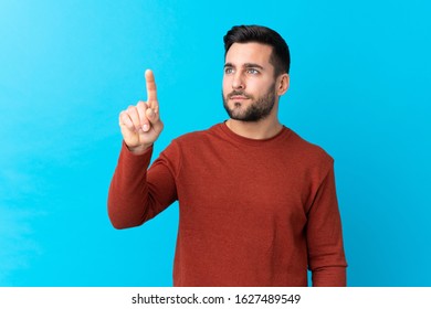 Young handsome man with beard over isolated blue background touching on transparent screen - Powered by Shutterstock