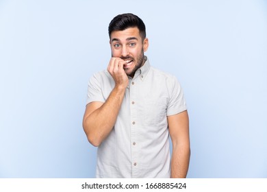 Young handsome man with beard over isolated blue background nervous and scared - Shutterstock ID 1668885424