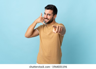 Young handsome man with beard over isolated background making phone gesture and pointing front - Shutterstock ID 1964031196