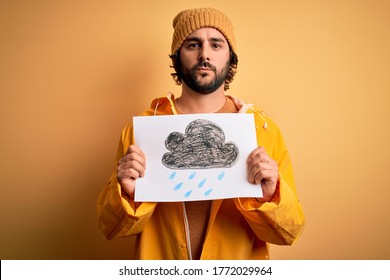 Young handsome man with beard wearing raincoat for rainy day holding banner with cloud with a confident expression on smart face thinking serious