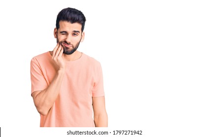 Young Handsome Man With Beard Wearing Casual T-shirt Touching Mouth With Hand With Painful Expression Because Of Toothache Or Dental Illness On Teeth. Dentist 