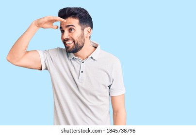 Young handsome man with beard wearing casual polo very happy and smiling looking far away with hand over head. searching concept.  - Shutterstock ID 1845738796