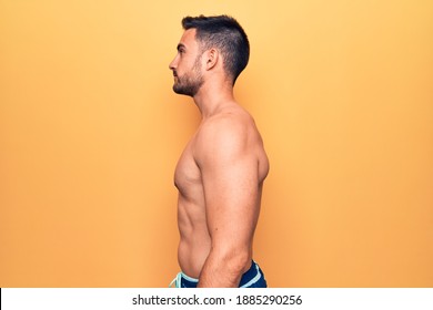 Young handsome man with beard wearing sleeveless t-shirt standing over yellow background looking to side, relax profile pose with natural face with confident smile. - Powered by Shutterstock