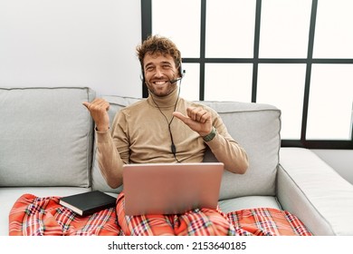 Young Handsome Man With Beard Wearing Operator Headset Working From Home Pointing To The Back Behind With Hand And Thumbs Up, Smiling Confident 