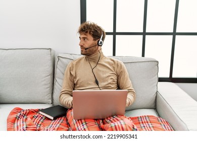 Young Handsome Man With Beard Wearing Operator Headset Working From Home Looking To Side, Relax Profile Pose With Natural Face And Confident Smile. 