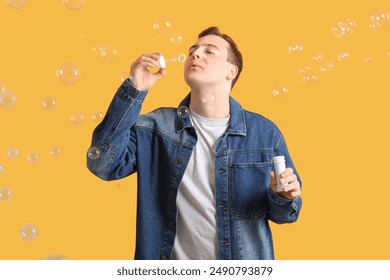 Young handsome man blowing soap bubbles on orange background - Powered by Shutterstock