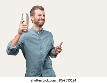 young handsome man, blue denim shirt, holding a beer pint, dancing or celebrating expression . person isolated against monochrome background