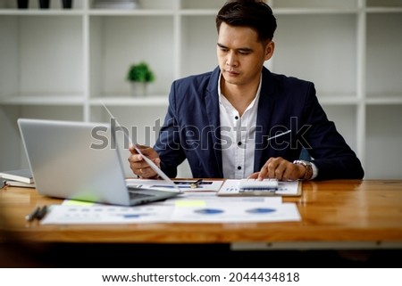 A young handsome man or businessman working on laptop computer in modern office. doing finances, accounting analysis, report data pointing graph Freelance education and technology concept.