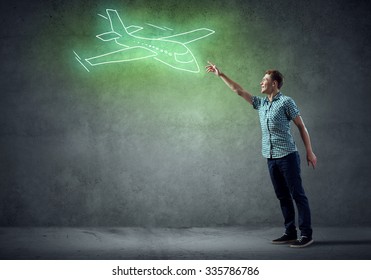 Young Handsome Man In Casual Reaching Hand To Touch Drawn Airplane On Wall