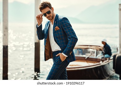 Young handsome man in classic suit wear sunglasses over the blurred lake 