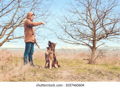 A young handsome man coaching a German shepherd while walking. Walk with a dog in winter or early spring. Dog training. Obedient dog. - Powered by Shutterstock