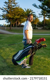 Young Handsome Man At The Course Carrying A Golf Bag.