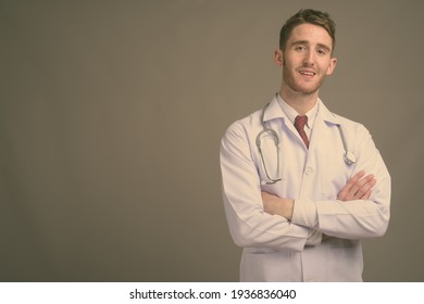 Young handsome man doctor against gray background