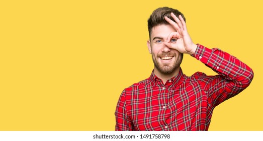 Young Handsome Man Doing Ok Gesture With Hand Smiling, Eye Looking Through Fingers With Happy Face.