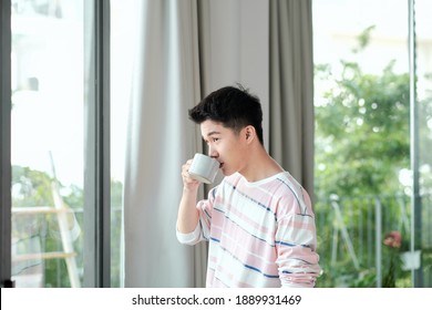 Young Handsome Man Drinking Morning Coffee By The Window In His Home