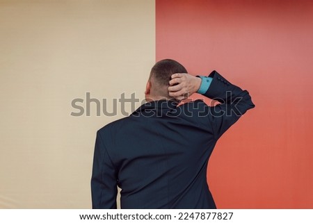 young handsome man feeling clueless and confused, thinking a solution, with hand on head, rear view. copy space for text. The concept of choice. a choice of two options