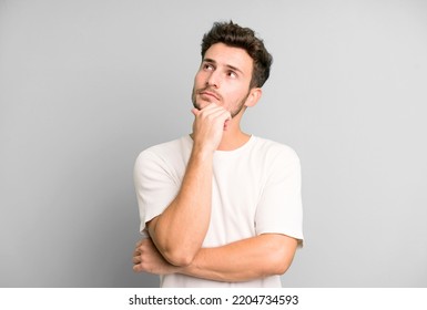 young handsome man feeling thoughtful, wondering or imagining ideas, daydreaming and looking up to copy space - Powered by Shutterstock